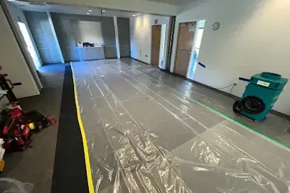 Plastic sheeting and a dehumidifier set up in a hallway during drying