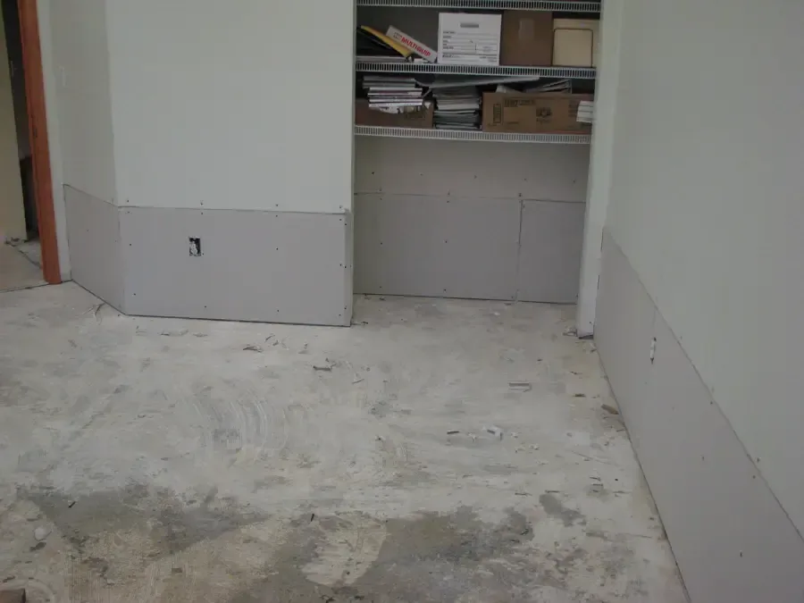 A room with the lower drywall removed so the wall cavities can dry